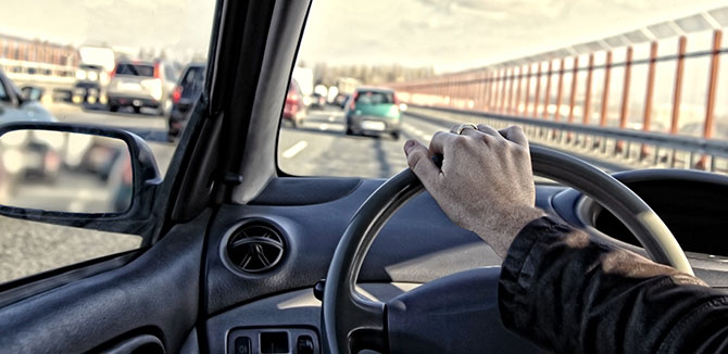 driver hand on the steering wheel on a highway