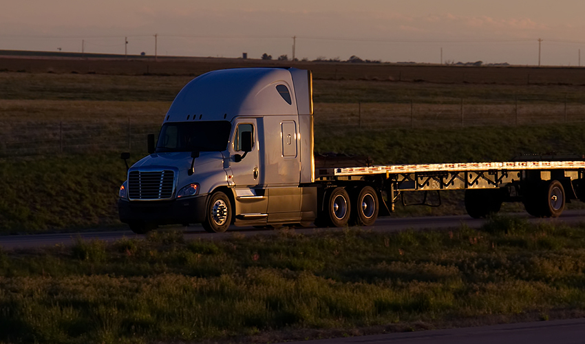 Flat bed truck driving down an open road