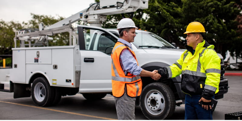 driver and coach shaking hands in front of a vehicle