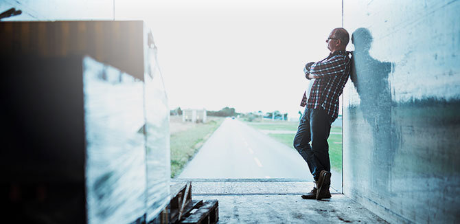 view from inside a long haul truck's trailer with a man standing inside casually leaning on the wall