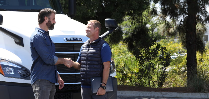 coach and driver shaking hands in front of a truck