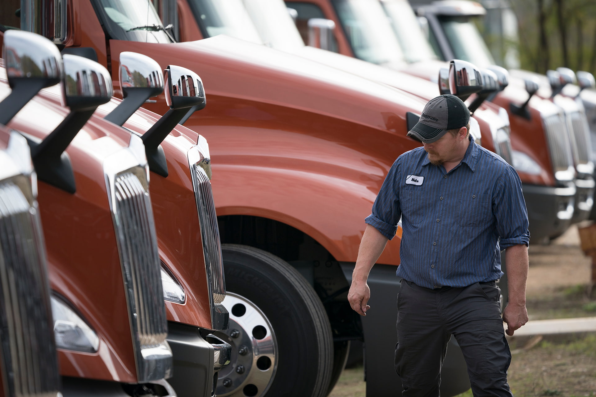 man walking along in front of a bunch of long haul trucks