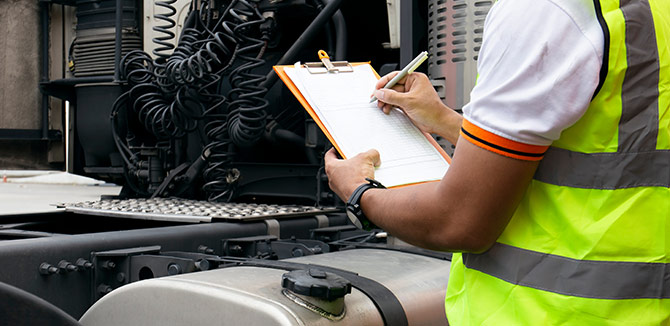 driver filling out a clip board standing next to a vehicle