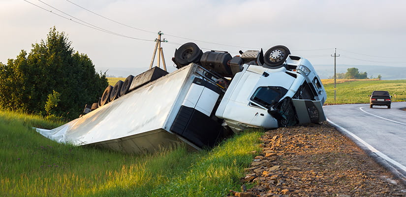 Crashed vehicle upside down on the side of the road