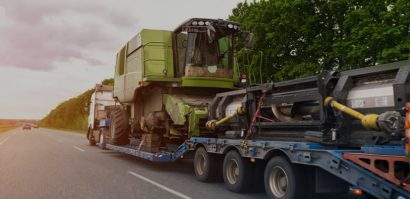 tractor being transported on a flatbed semi trailer 