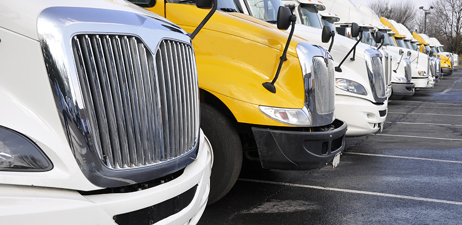 white and yellow semi truck trailers lined up in parking lot 