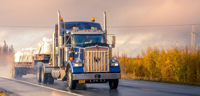 flatbed truck driving on a wet road